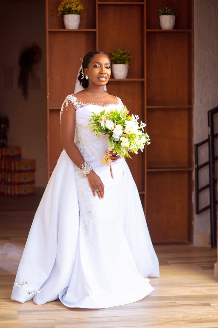 Bride in white beaded gown with overskirt and bouquet